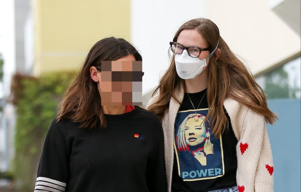 a woman wearing a power t-shirt walks with another woman