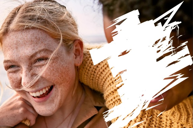 a woman with freckles smiles while a man holds her shoulder