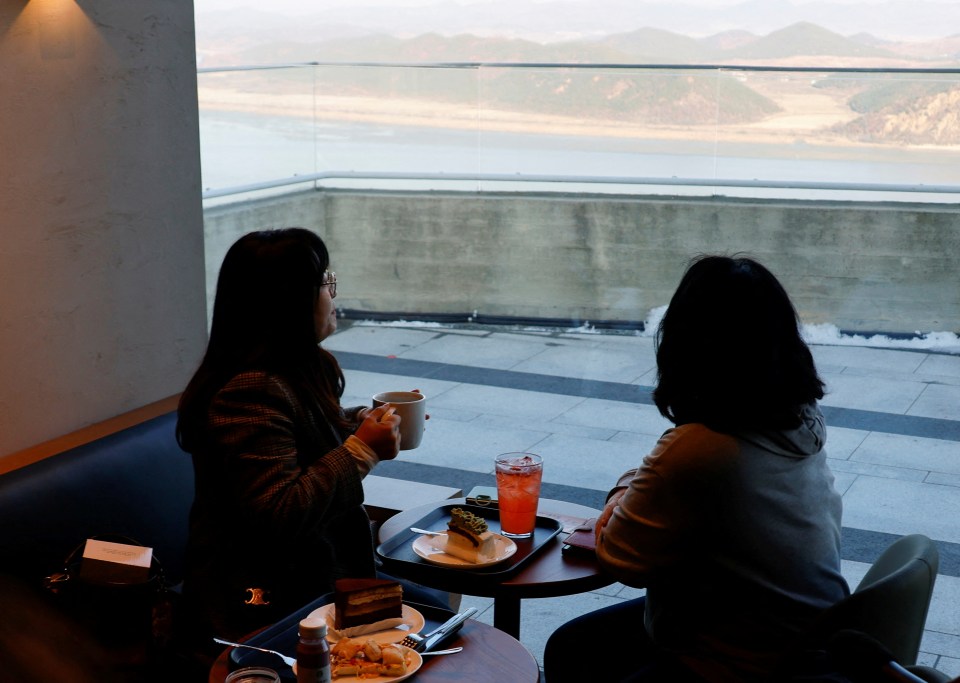 Customers look at North Korea’s propaganda village Kaepoong, in the new Starbucks store at the top of the Aegibong Peak Observatory