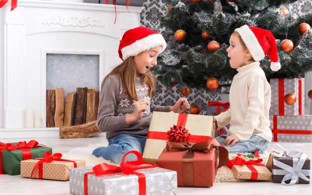 a boy and a girl are opening christmas presents