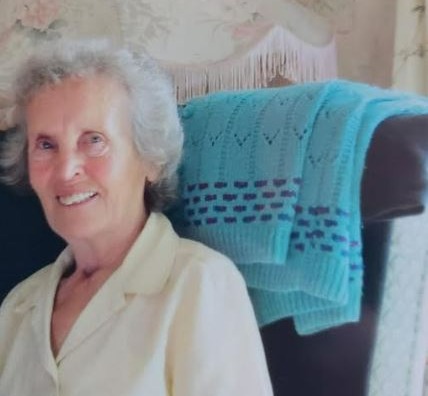 an elderly woman is sitting in a chair next to a lamp .