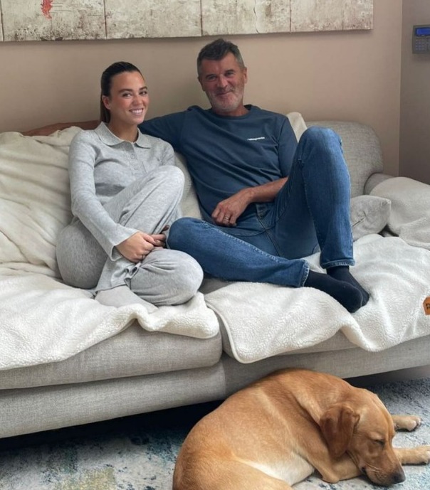 a man and woman sit on a couch next to a dog