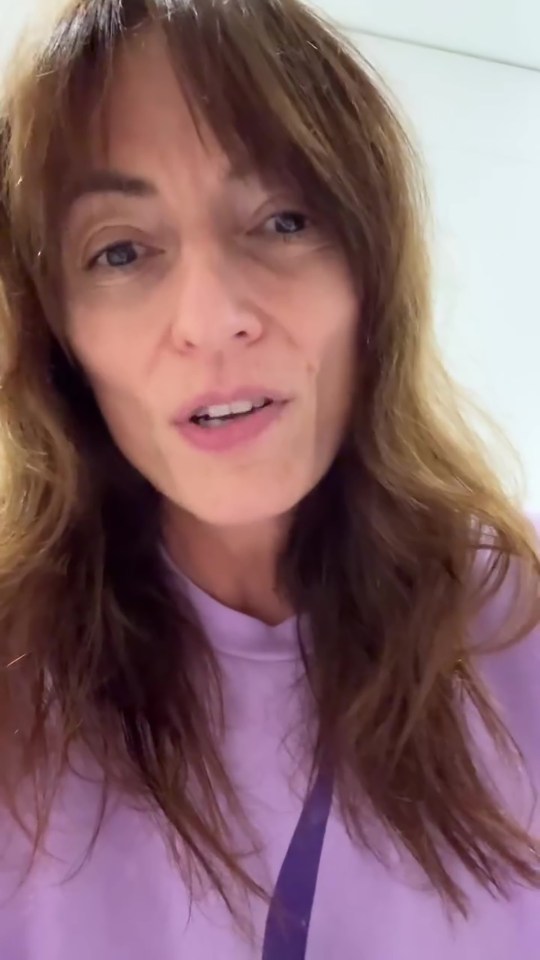 a woman with long hair is wearing a purple shirt and talking .