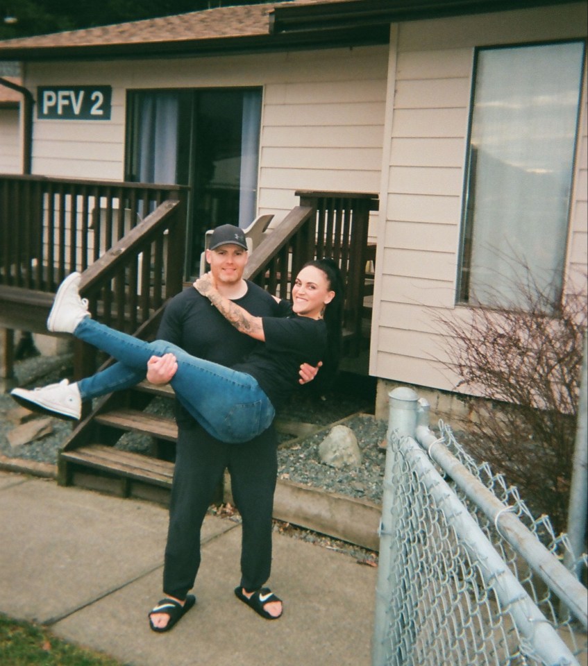 a man carrying a woman in front of a house with pfv 2 on it