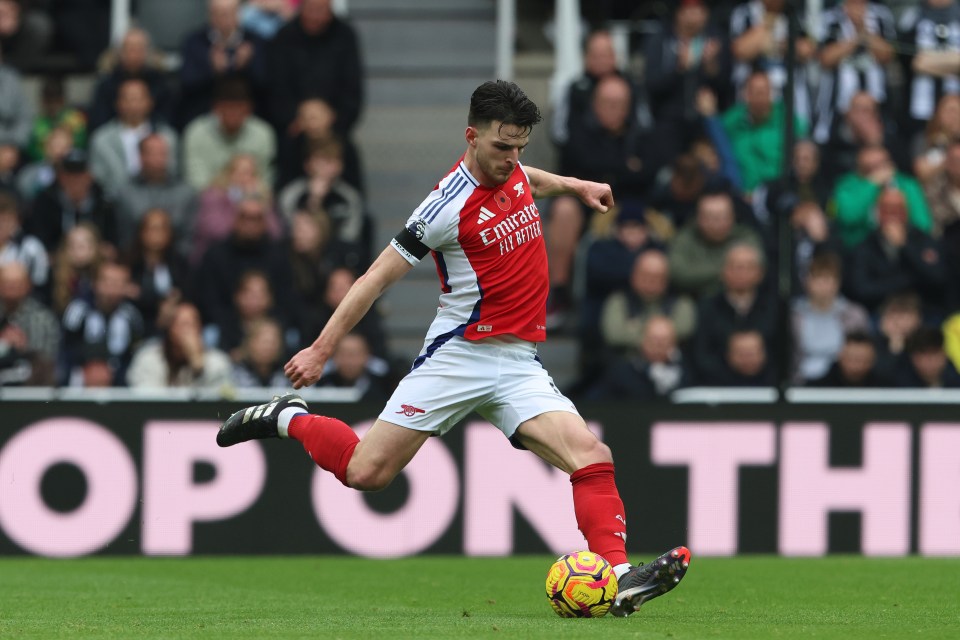 a soccer player wearing a red and white jersey that says fly emirates on it