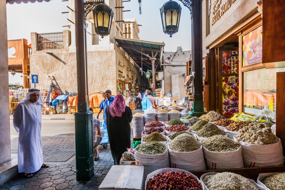 a woman stands in front of a store that sells spices