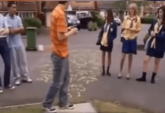 a man in an orange shirt is standing in front of a group of people .