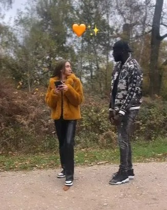 a man and a woman are standing next to each other on a dirt road .