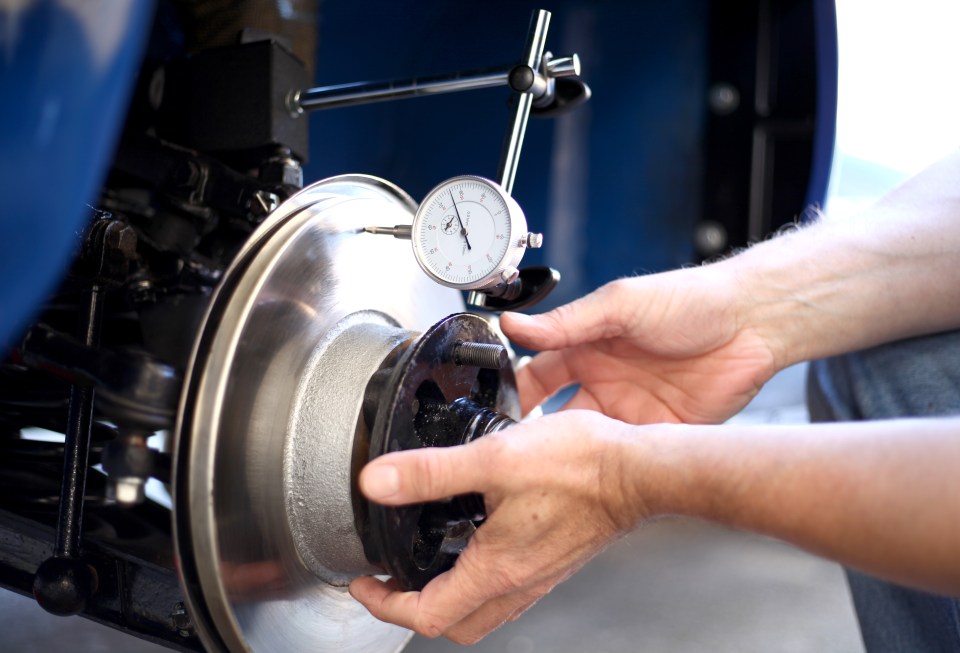 a man is measuring a brake disc with a dial that says ' a ' on it