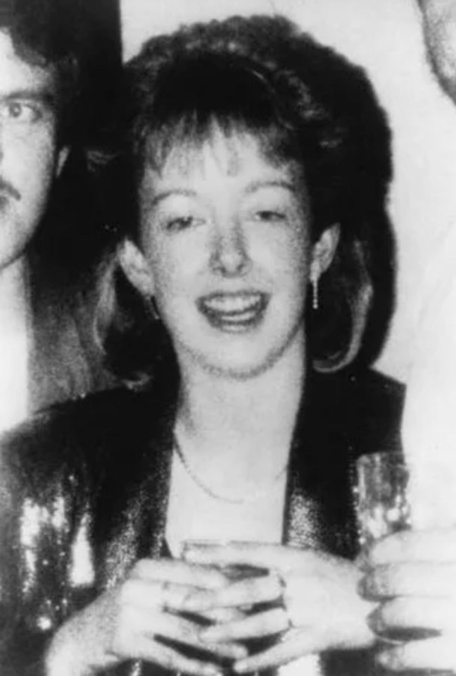 a woman is holding a glass of wine and smiling in a black and white photo .