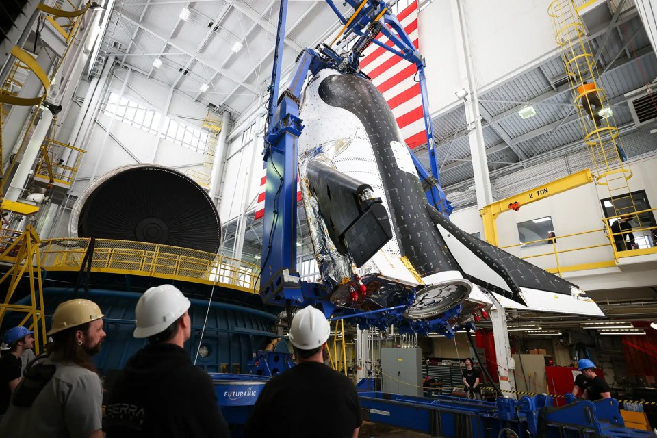 a group of men in hard hats are looking at a space shuttle