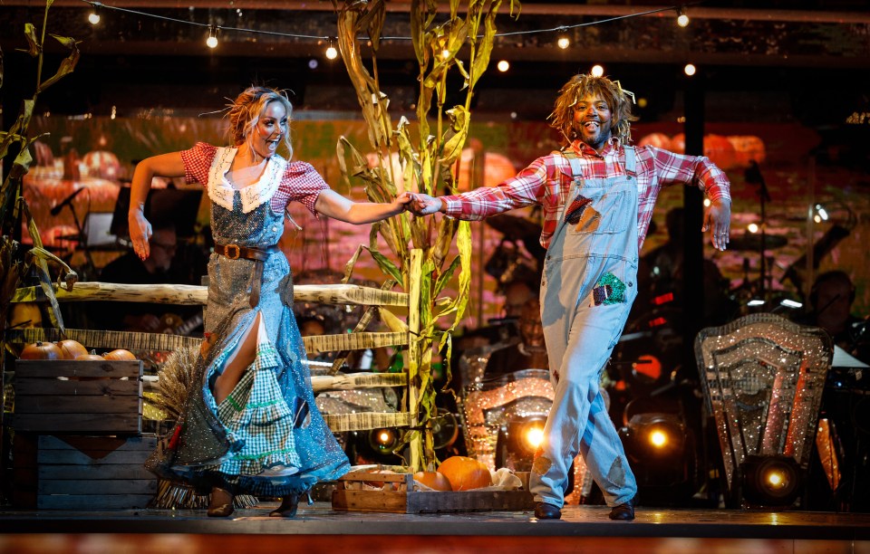 a man in overalls is dancing with a woman in a blue dress