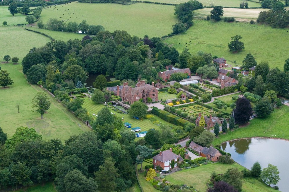 a large house sits in the middle of a lush green field