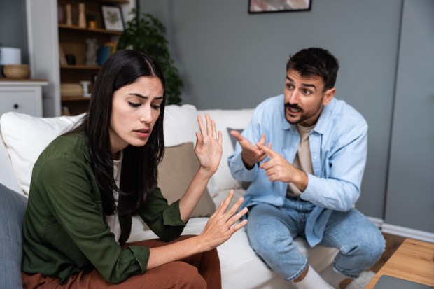 a man and a woman are sitting on a couch having an argument