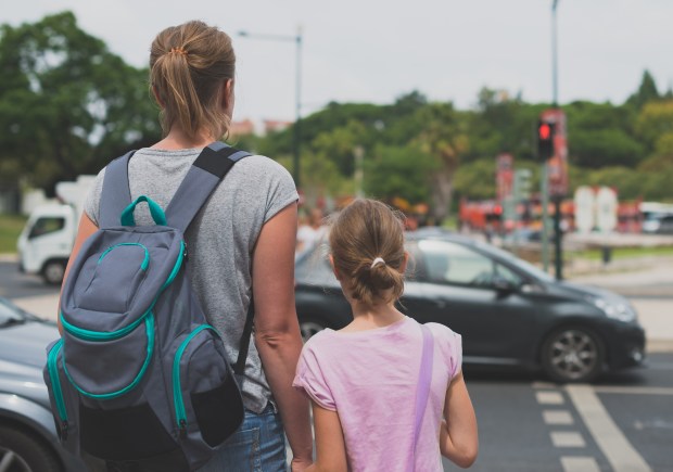 a woman with a backpack holds the hand of a little girl