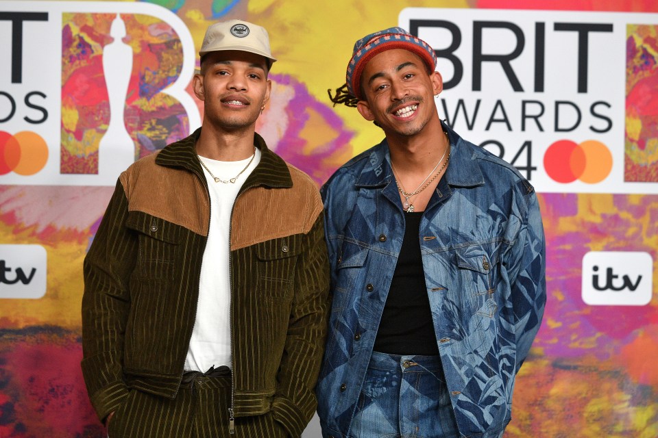 two men standing in front of a brit awards sign