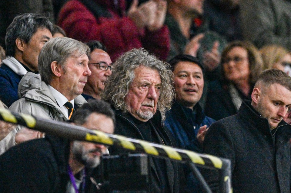 a man with curly hair sits in a crowd of people