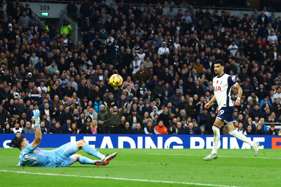 a soccer player wearing a tottenham jersey kicks the ball