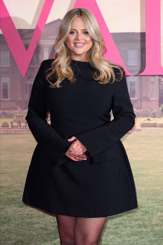 a woman in a black dress stands in front of a large pink v