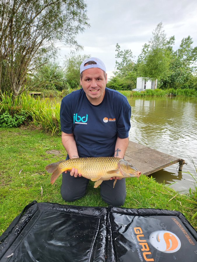 Adrian Lewis, former darts world champion, holding a large carp he caught while fishing.