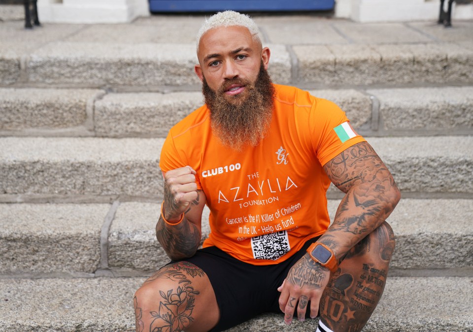 a man with a beard wears an orange shirt that says club 100 the azylia foundation