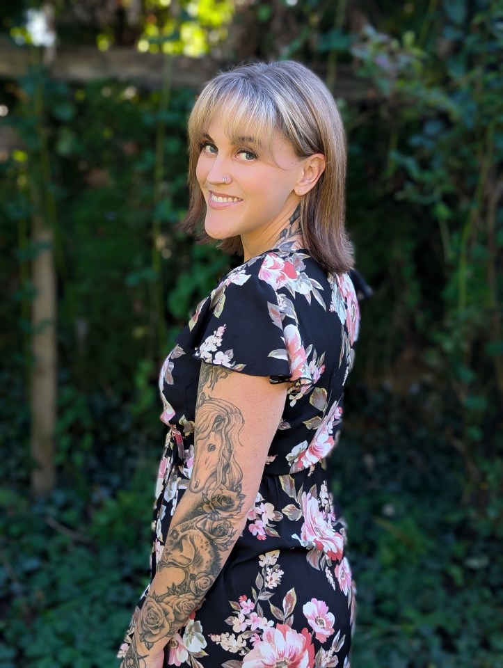 a woman with a tattoo on her arm is wearing a floral dress