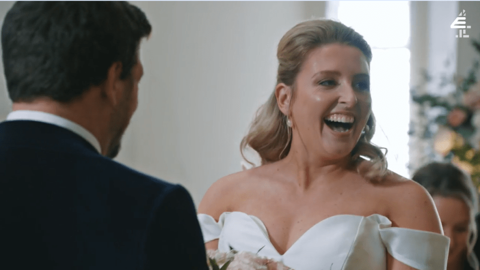 a woman in a wedding dress laughs while standing next to a man in a suit