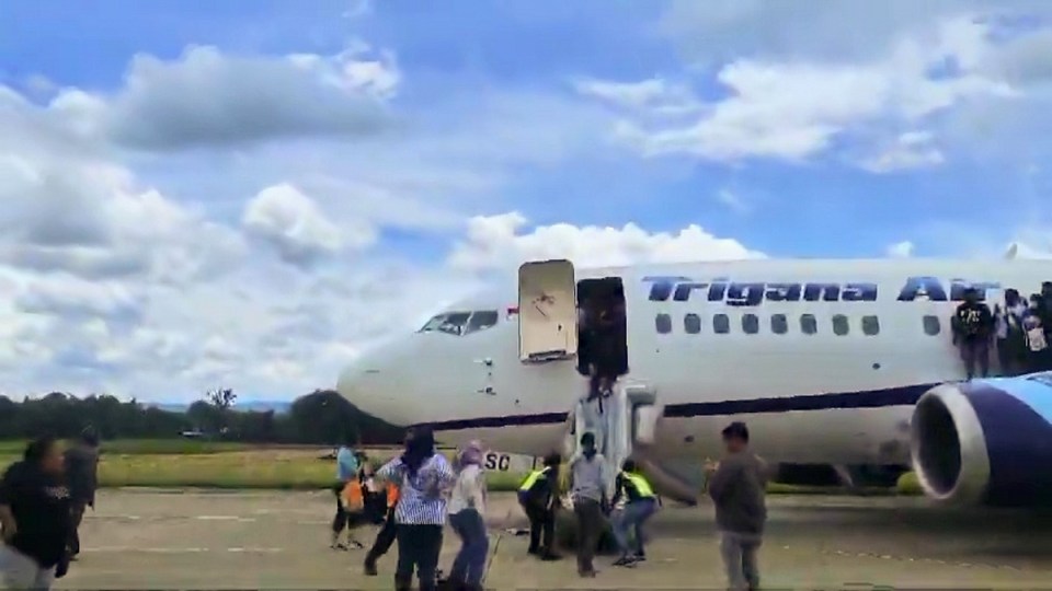 people are boarding a trigana airplane on the tarmac