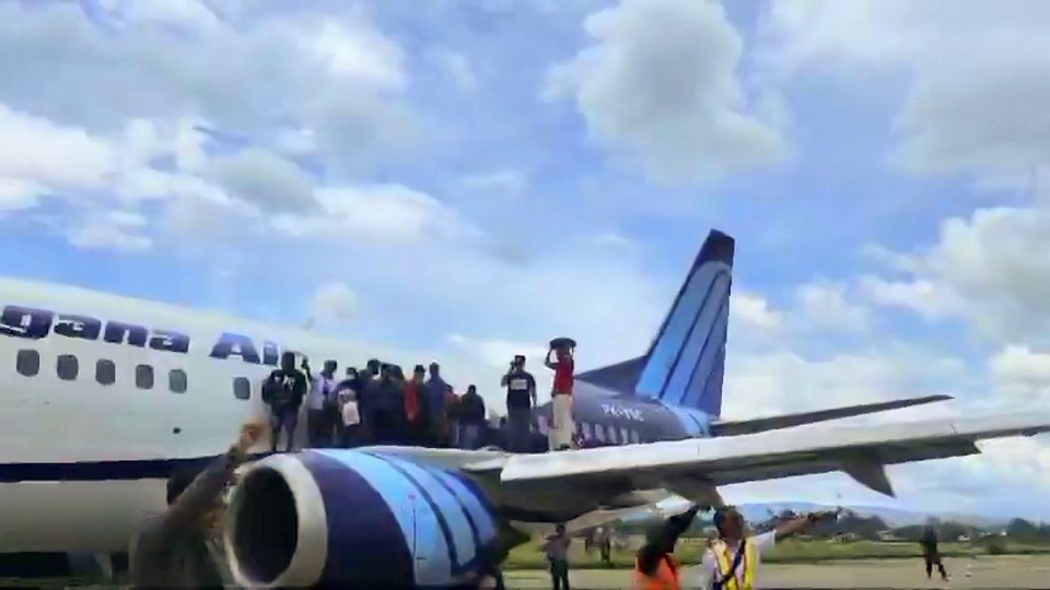 Dozens of flyers could be seen exiting the plane through the emergency exit