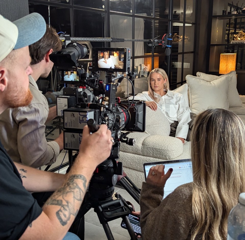 a woman sits on a couch in front of a camera with the number 150 on it