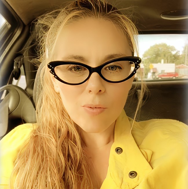 a woman wearing glasses and a yellow jacket is sitting in a car