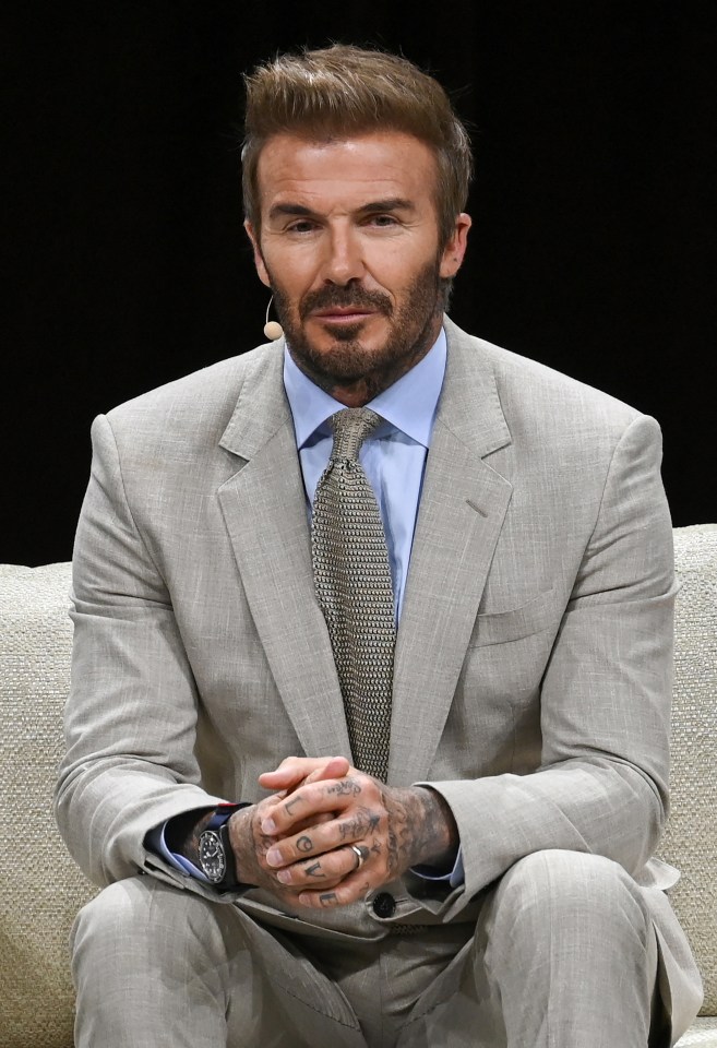 a man in a suit and tie sits with his hands folded