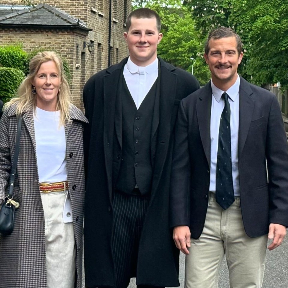 a man in a suit stands next to a woman and a man in a tie