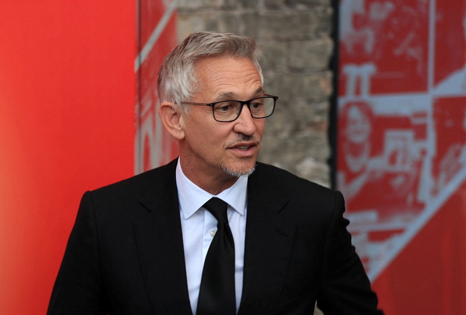 a man wearing glasses and a suit stands in front of a red wall