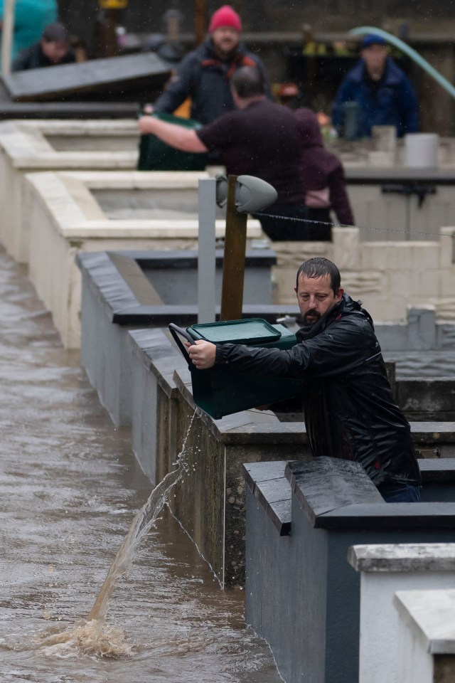 Locals pour water out from their front gardens on Sion Street in Pontypridd, Wales this morning