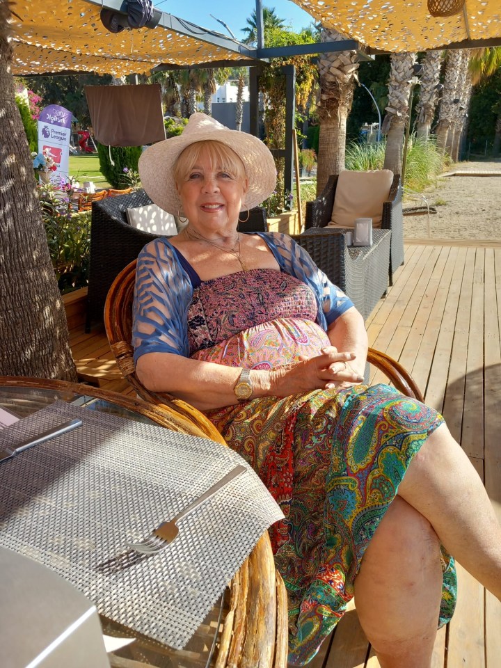 a woman wearing a hat sits on a wooden deck