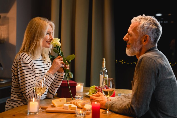 a woman is giving a rose to a man at a table