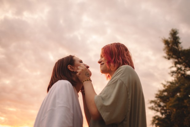 a woman with a tattoo on her wrist is touching another woman 's face