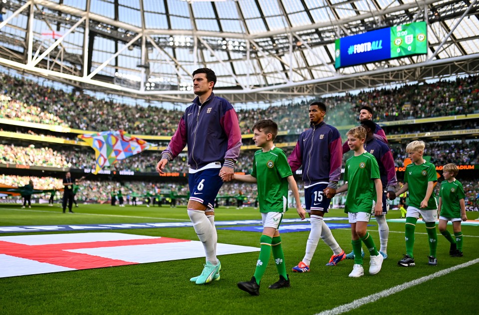 a group of soccer players are walking on a field with a large screen behind them that says football