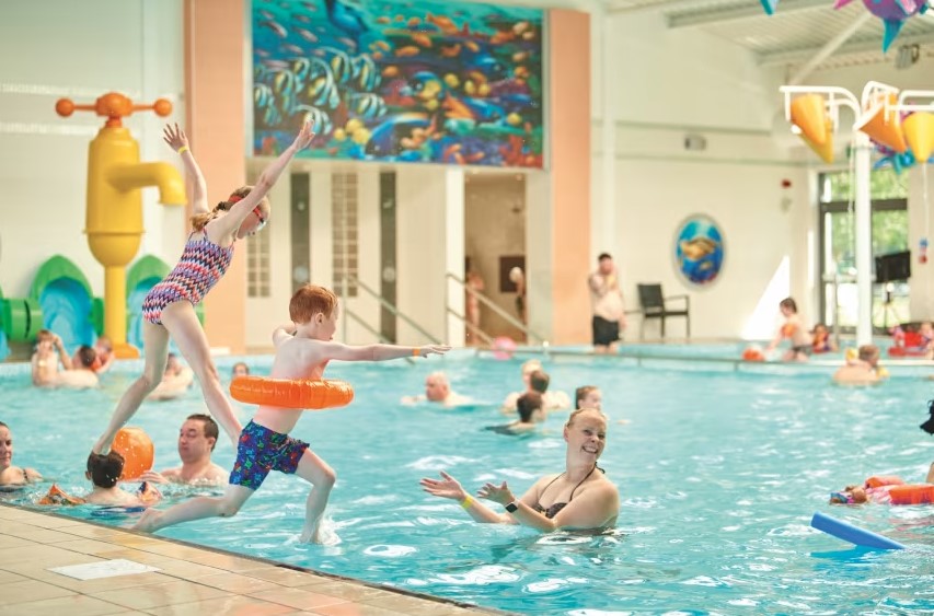 a girl in a bathing suit jumps into a swimming pool