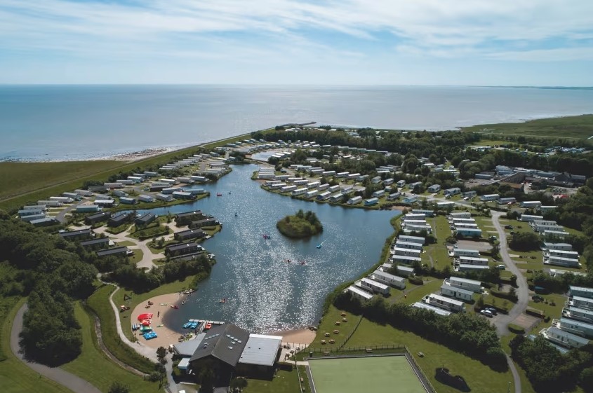 an aerial view of a caravan park with a small island in the middle of the lake