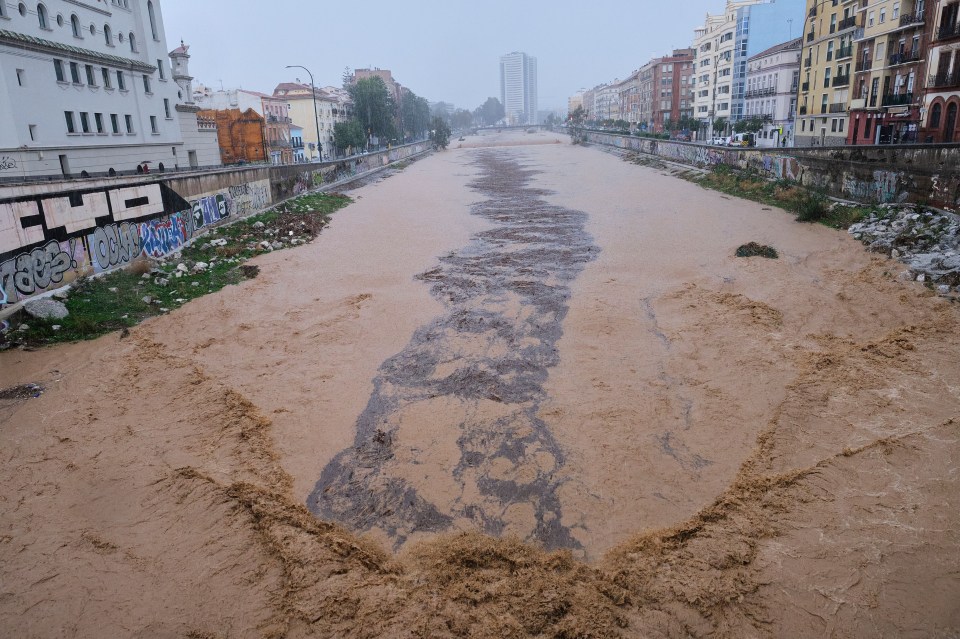 a flooded river with graffiti on the side of it including the word cho