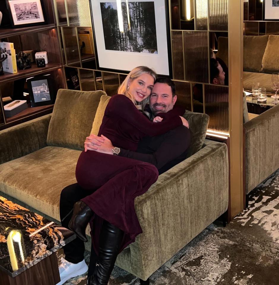 a man and a woman are sitting on a couch with a picture of a forest on the wall behind them