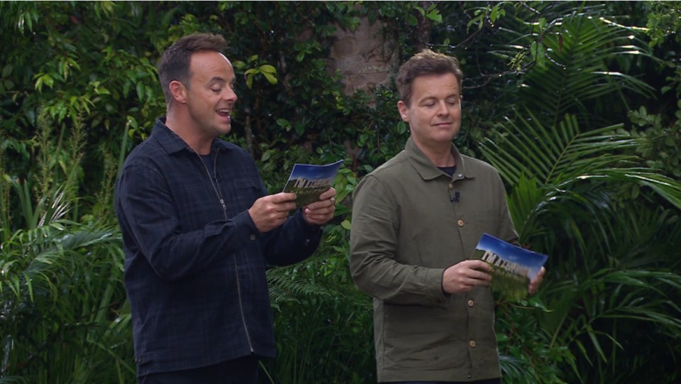 two men holding a card that says ' i 'm a celebrity ' on it