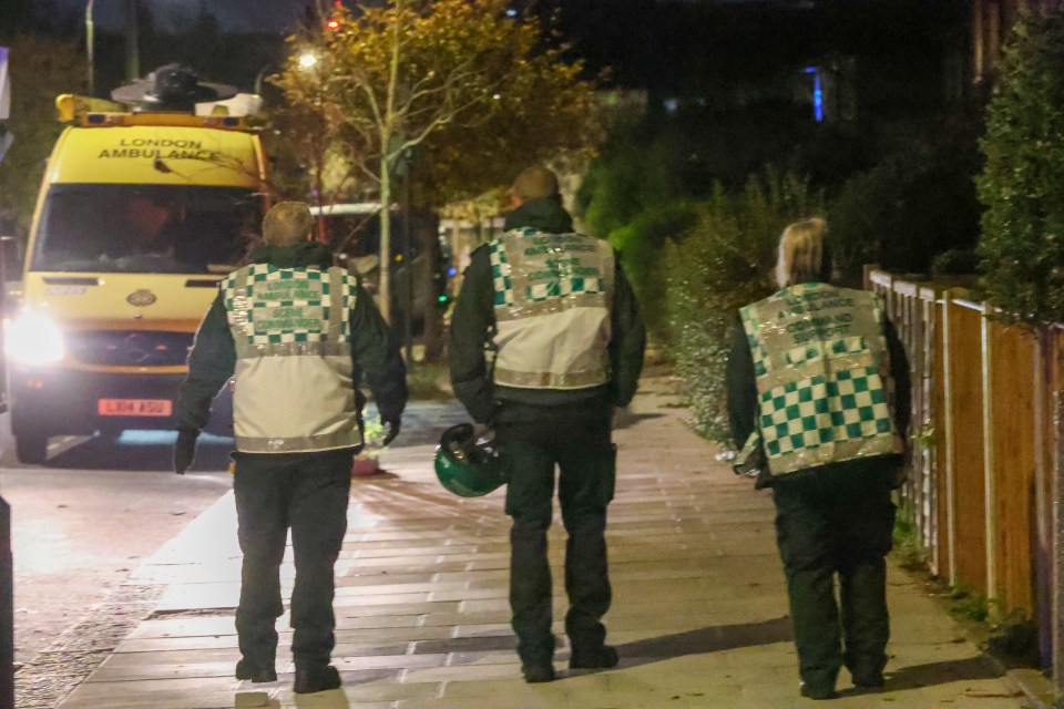 three london ambulance officers are walking down a sidewalk