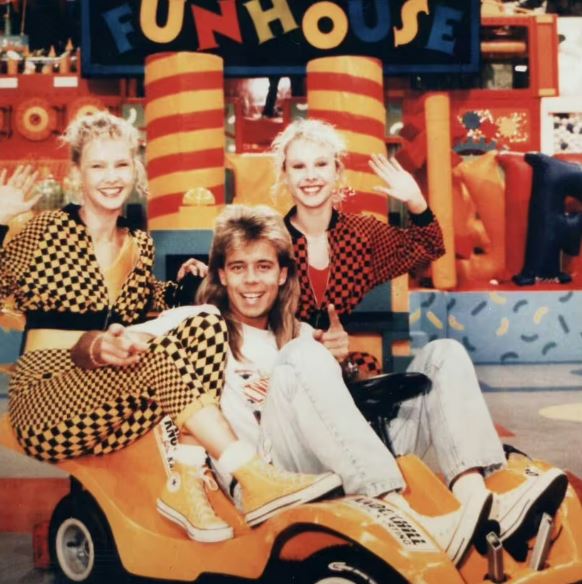 a man and two women pose in front of a sign that says funhouse