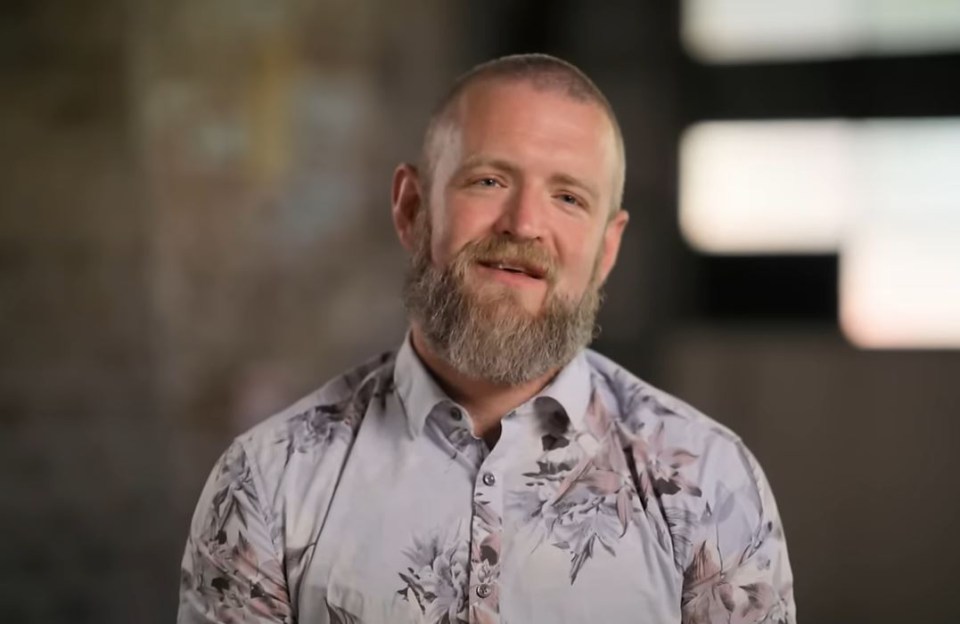 a man with a beard is wearing a floral shirt