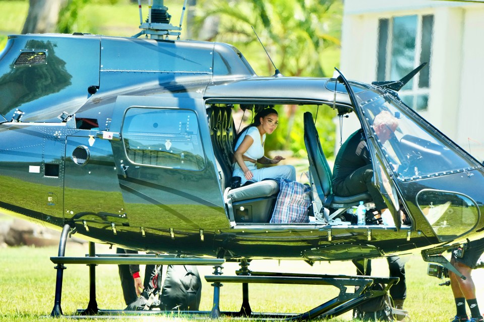 a woman sits in the back of a black helicopter