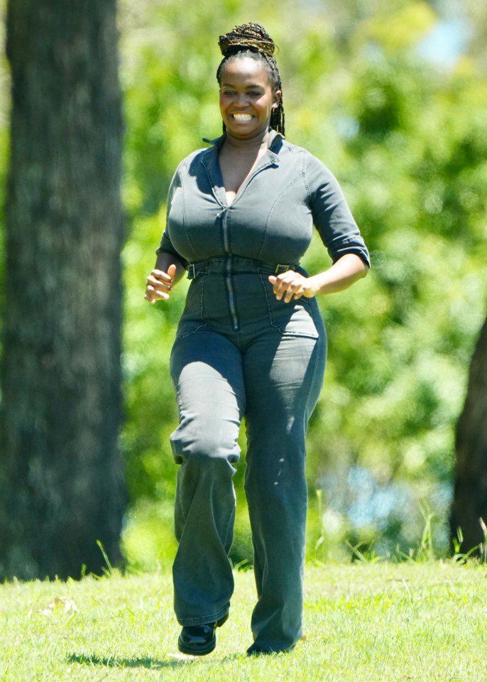 a woman in a grey jumpsuit is running in the grass