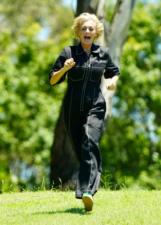 a woman in a black jumpsuit is running in the grass